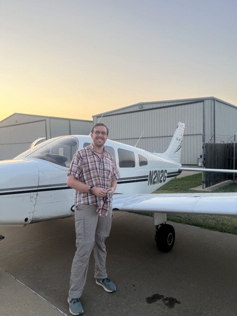 Josh holding his shirt tails in front of the plane