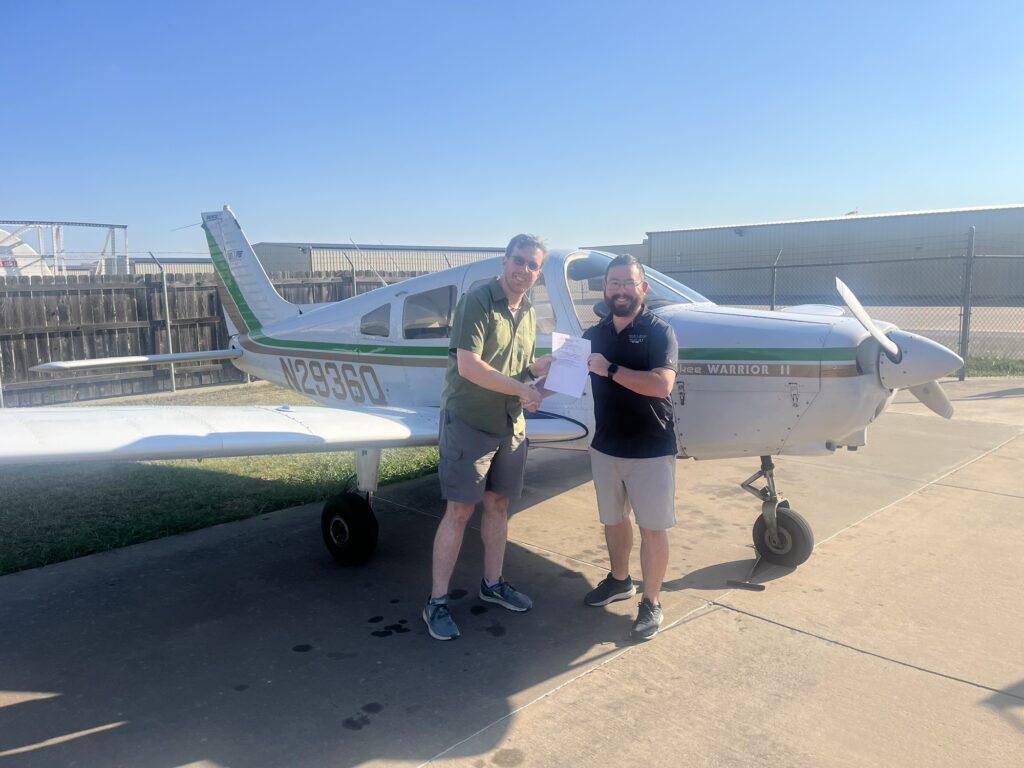 Standing in front of the plane with instructor Nathan with my new license!